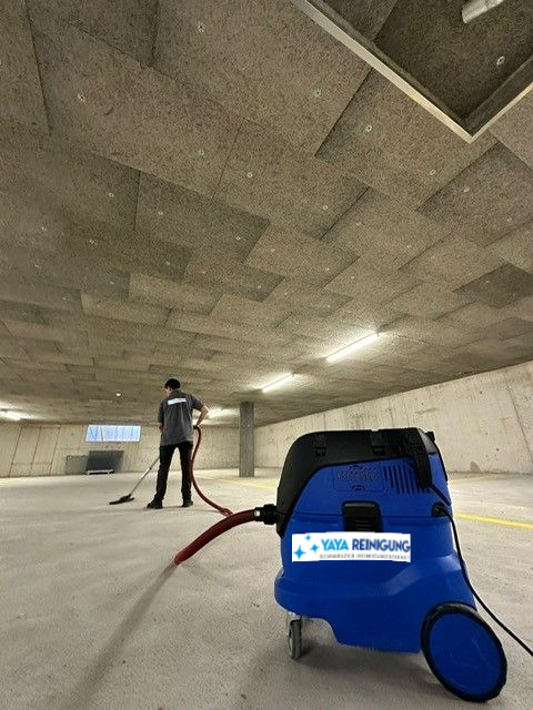 Mitarbeiter saugt eine Betonhalle, im Vordergrund der Sauger mit Yaya-Aufkleber