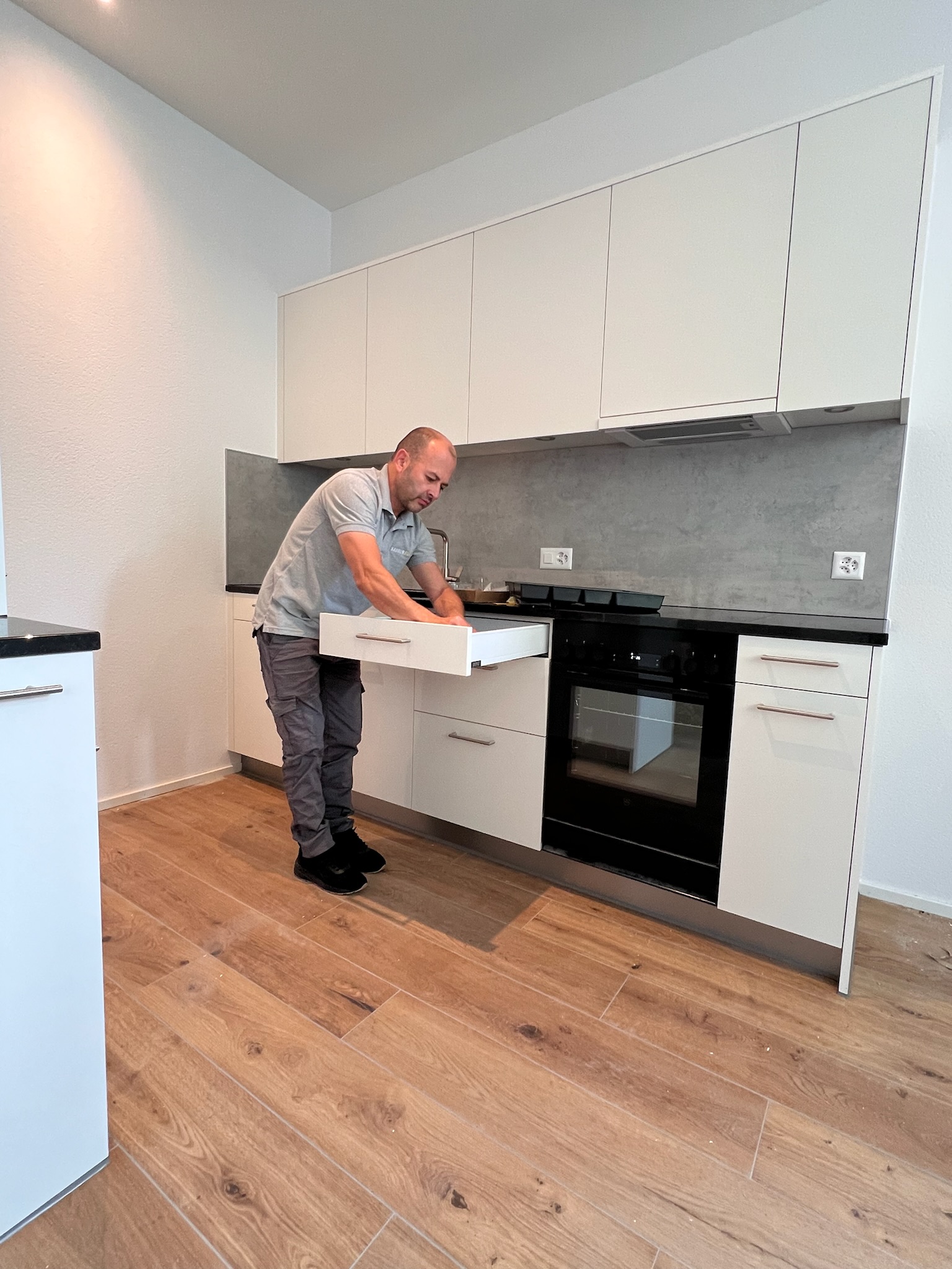 Mitarbeiter reinigt eine Schublade in einer neuen weissen Küche