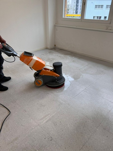 Orange Scheuersaugmaschine auf einem Steinboden im Einsatz
